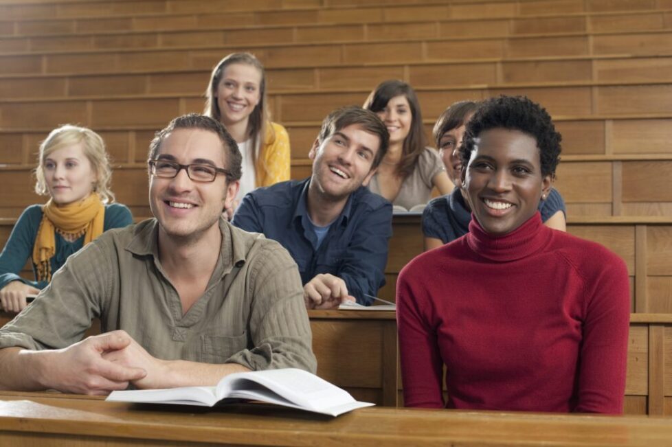 Germany, Leipzig, Group of university students studying in classroom, smiling